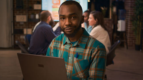 Portrait of man using laptop while sitting in cafe