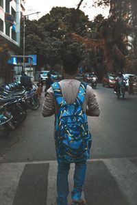 Rear view of man walking on road in city