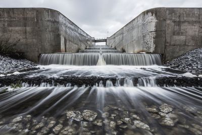 Water flowing in dam against sky