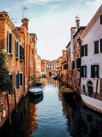 Canal amidst buildings in city against sky