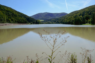 Scenic view of lake by mountains against sky