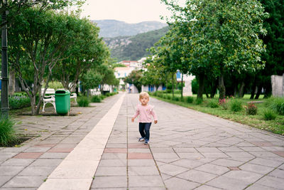 Rear view of woman walking on footpath amidst trees