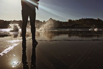 Low section of silhouette man standing in water