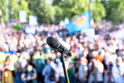 Focus on microphone, blurred group of people at mass protest in the background