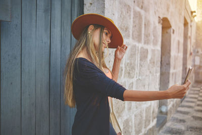 Portrait of young woman standing against wall