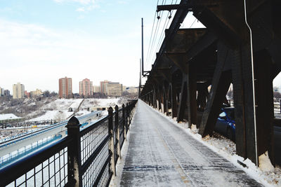 Bridge over road amidst buildings in city against sky