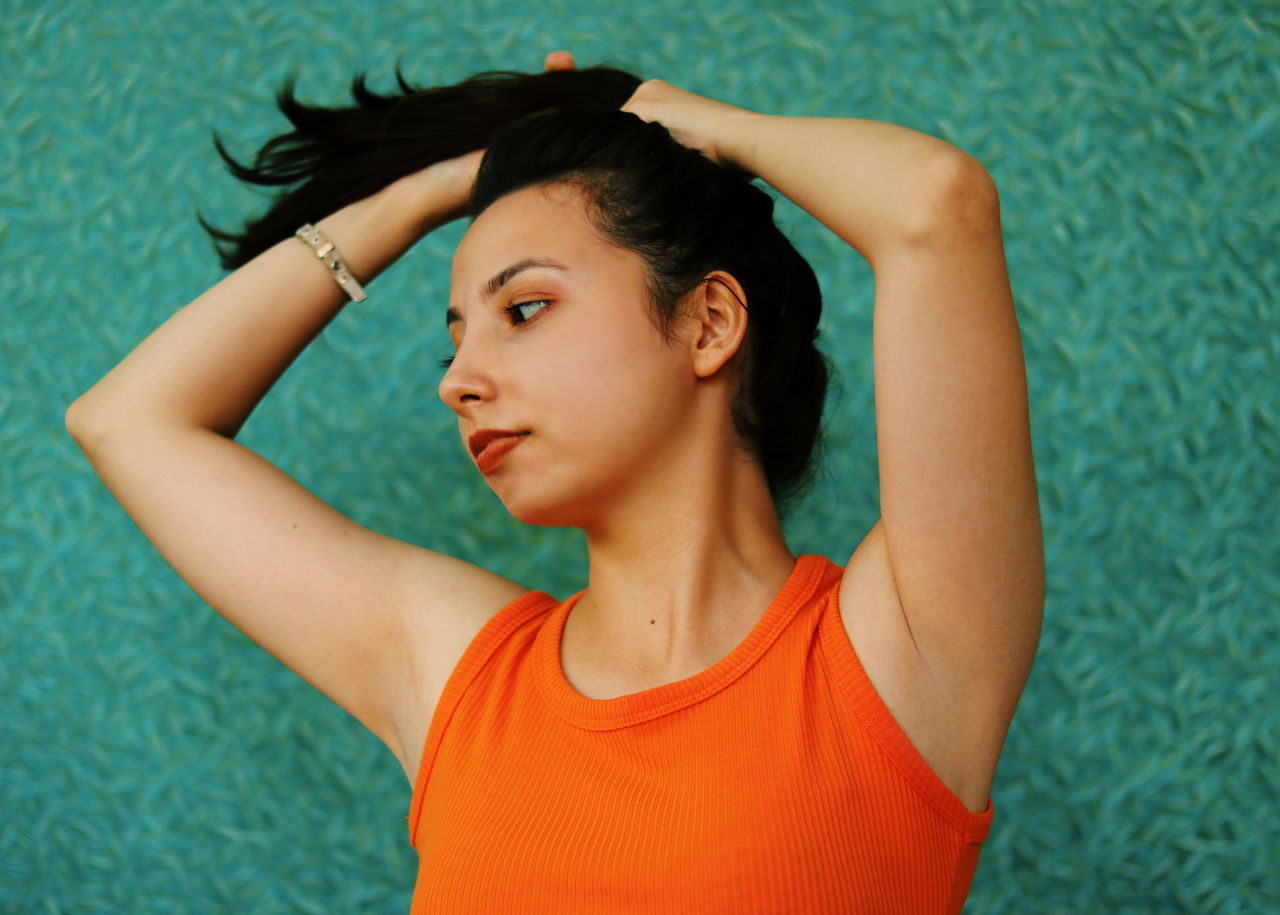 one person, young adult, portrait, front view, headshot, hairstyle, hair, lifestyles, young women, hand in hair, indoors, black hair, beauty, lying down, waist up, looking, real people, casual clothing, beautiful woman, human arm, arms raised, contemplation, hands behind head