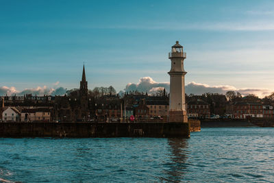View of buildings by sea against sky in city