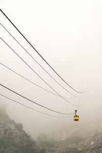 Overhead cable car against sky during foggy weather