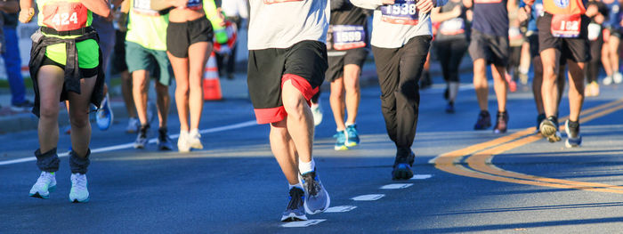 The lower body of many runners running in a marathon on a road in long island.