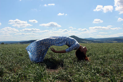 Side view of woman bending backwards on grassy mountain