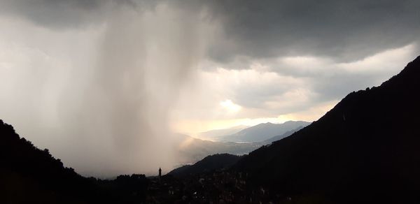 Panoramic shot of silhouette mountains against storm clouds