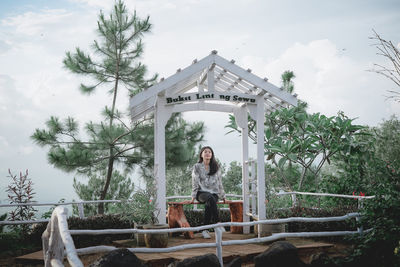 Woman standing by tree against sky