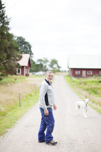Senior farmer walking on road with his dog
