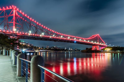 Illuminated bridge over river against sky at night