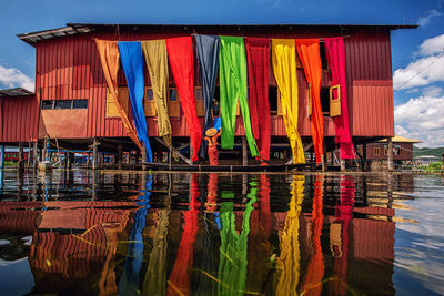 Multi colored umbrellas hanging by lake against sky