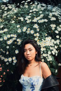 Portrait of beautiful woman standing by flowering plant