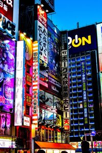 Information sign on illuminated street amidst buildings in city at night