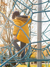 Little boy on children playground. kid climbs on rope structure on sports field. leisure activity