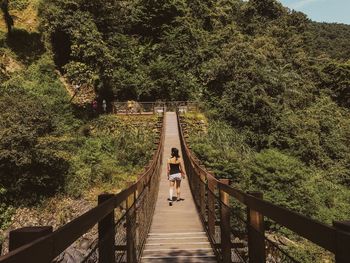 Rear view of woman walking on footbridge