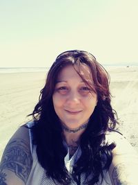 Portrait of smiling young woman on beach against sky