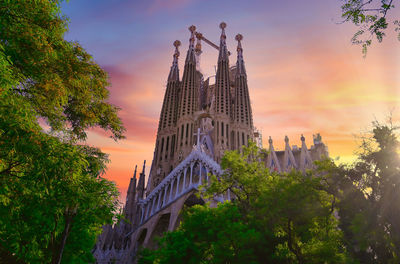 Low angle view of trees and building against sky