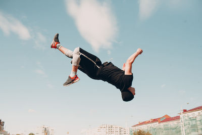 Low angle view of man jumping against sky