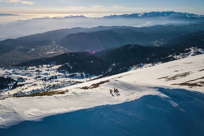 Aerial view of people skiing on snowcapped mountain against sky