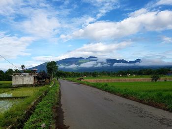 Road amidst field against sky