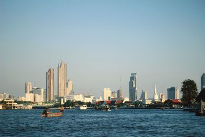 Sea by modern buildings against clear sky in city