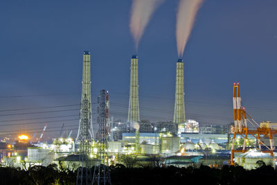 Illuminated factory against sky at night