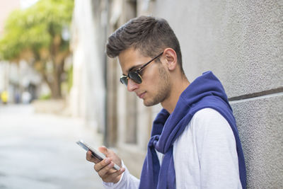 Portrait of young teenage man with mobile phone on the street