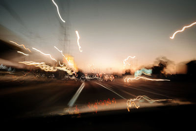 Light trails on street against sky at night