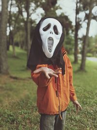 Boy wearing monster mask on grassy field