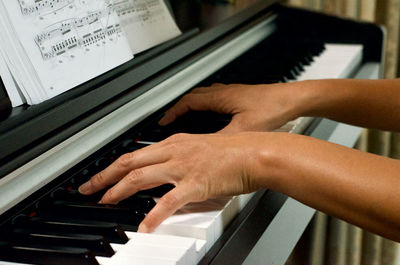 Cropped hands of woman playing piano