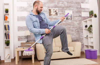 Full length of man sitting on sofa at home