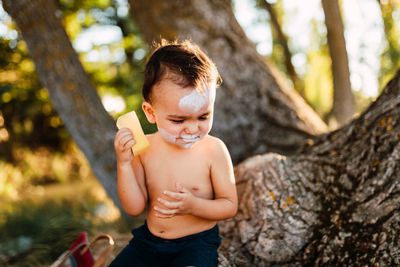 Full length of shirtless boy in tree trunk