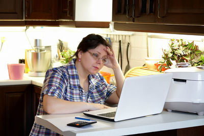 Young woman using mobile phone while sitting on table