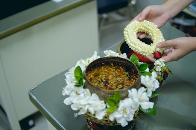 Cropped hands holding white flowers by food