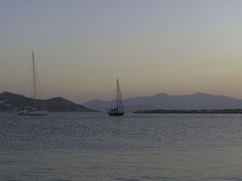 Sailboat sailing on sea against sky during sunset - behind the breakwater, sunset at naxos