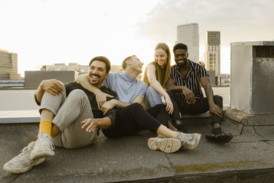 Cheerful group of male and female friends having fun while sitting on terrace