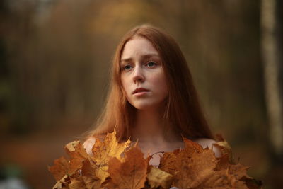 Thoughtful young woman with redhead at forest during autumn