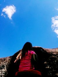 Rear view of woman sitting against blue sky