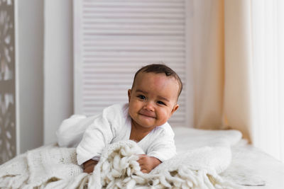 Portrait of cute baby boy on bed at home
