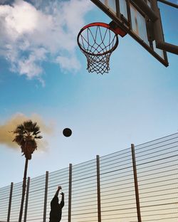 Person playing basketball against sky