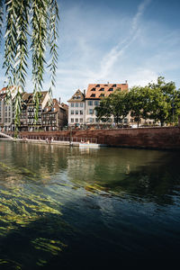 Buildings by lake against sky in city