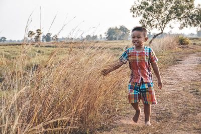 Full length portrait of happy girl standing on field