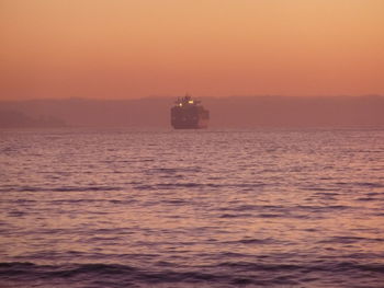 Boat sailing in sea at sunset