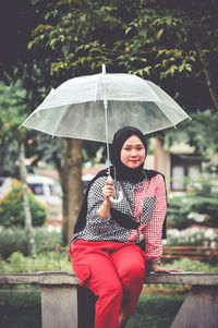 Portrait of woman with umbrella standing in rain during rainy season