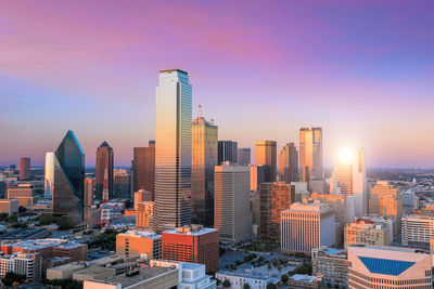 Modern buildings in city against sky during sunset